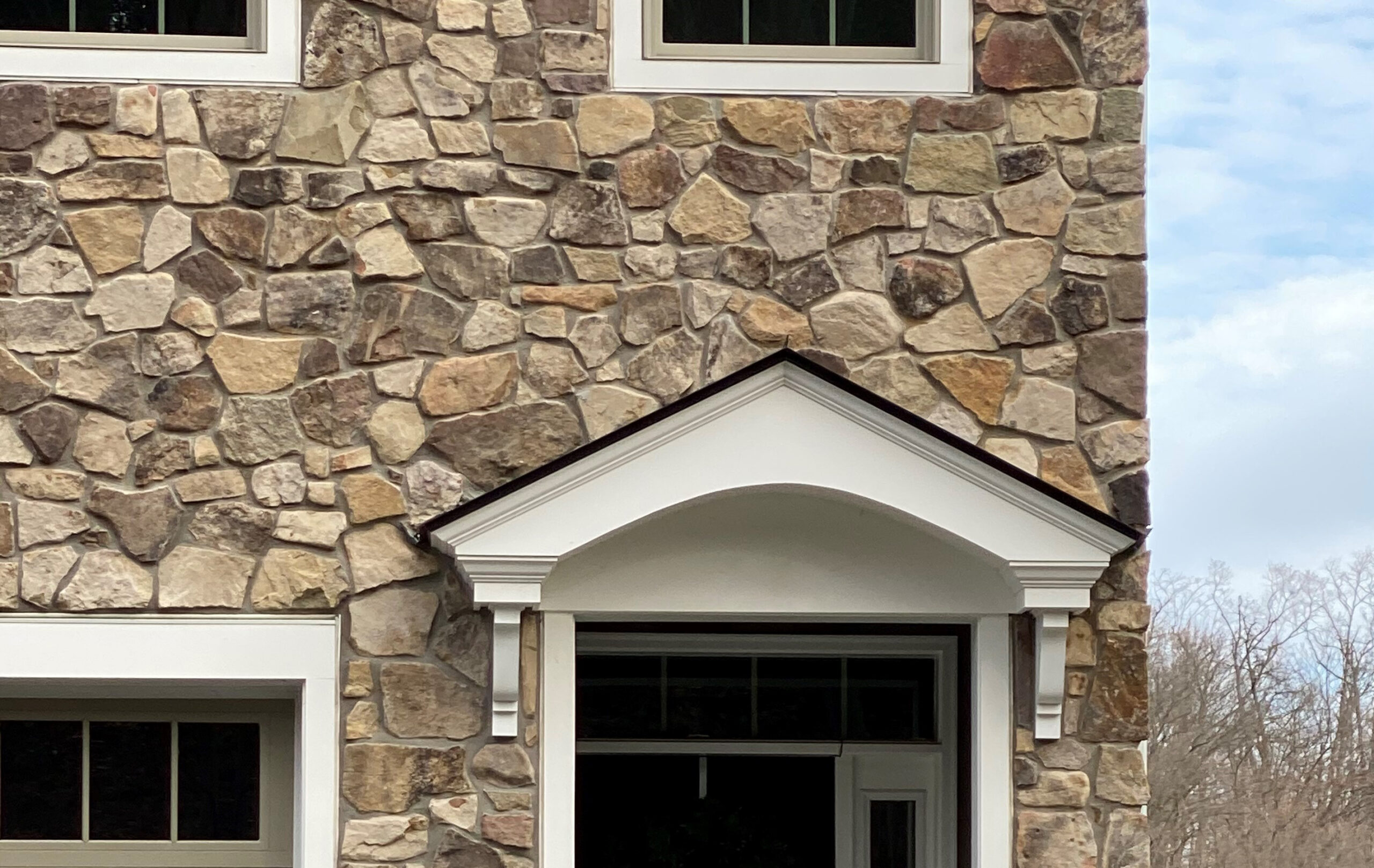 brown mosaic real stone veneer installed on a townhouse with white trim